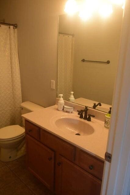 bathroom featuring tile patterned floors, toilet, curtained shower, and vanity