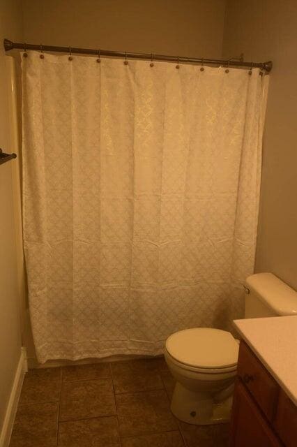 bathroom with tile patterned flooring, vanity, toilet, and a shower with shower curtain