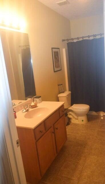 bathroom with curtained shower, toilet, and vanity