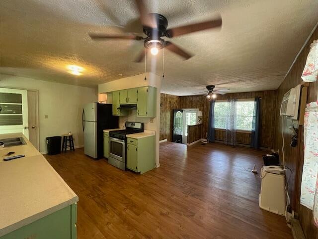 kitchen with wood walls, dark hardwood / wood-style flooring, appliances with stainless steel finishes, ceiling fan, and green cabinetry