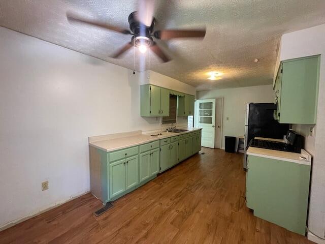 kitchen featuring a textured ceiling, dark hardwood / wood-style flooring, sink, ceiling fan, and green cabinetry