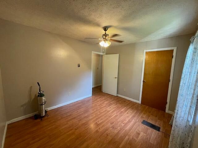 interior space featuring ceiling fan, wood-type flooring, and a textured ceiling