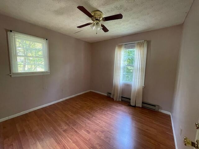 unfurnished room featuring a baseboard heating unit, a textured ceiling, hardwood / wood-style floors, and ceiling fan