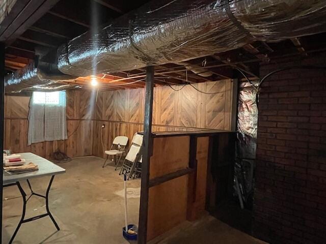 basement featuring brick wall and wooden walls