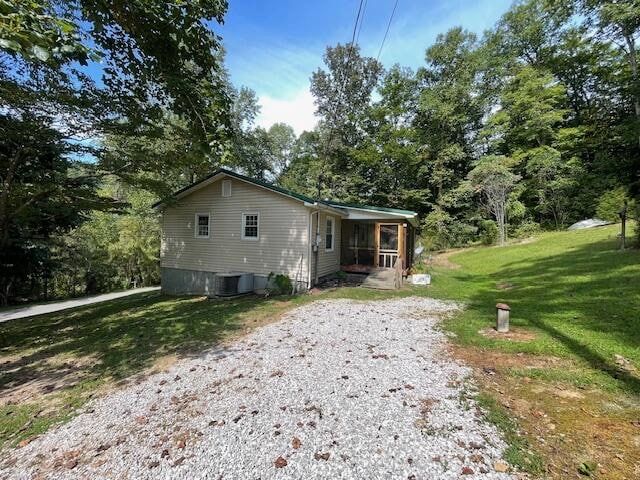 view of side of property with central air condition unit and a lawn