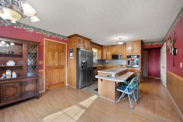 kitchen featuring a breakfast bar, a kitchen island, stainless steel appliances, and light hardwood / wood-style floors