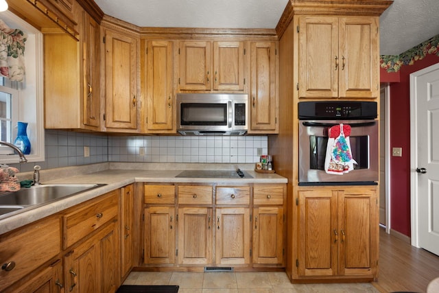 kitchen with tasteful backsplash, sink, stainless steel appliances, and a textured ceiling