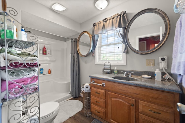 bathroom featuring a shower with shower curtain, hardwood / wood-style floors, vanity, and toilet