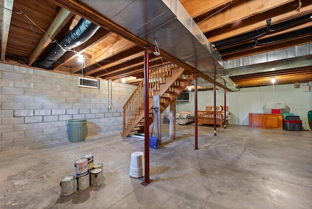 unfinished basement with stairs and concrete block wall