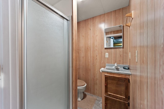 bathroom with vanity, wooden walls, tile patterned flooring, toilet, and an enclosed shower