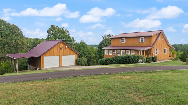 view of front of home featuring metal roof, a detached garage, an outbuilding, and a front yard