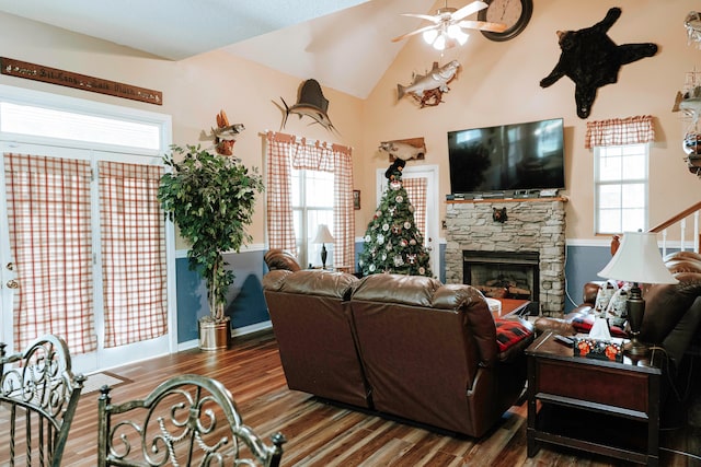 living room with lofted ceiling, dark hardwood / wood-style flooring, ceiling fan, and a stone fireplace