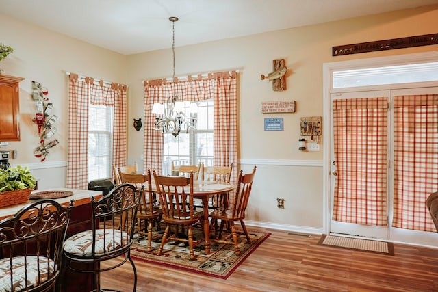 dining space with hardwood / wood-style floors and a chandelier