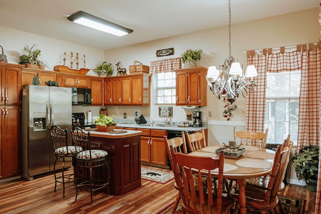 kitchen with black appliances, a healthy amount of sunlight, a notable chandelier, and a kitchen island