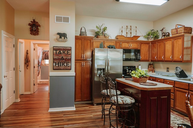 kitchen featuring dark wood-type flooring, black appliances, and a kitchen island