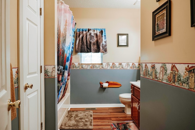 full bathroom featuring toilet, vanity, a textured ceiling, wood-type flooring, and shower / tub combo