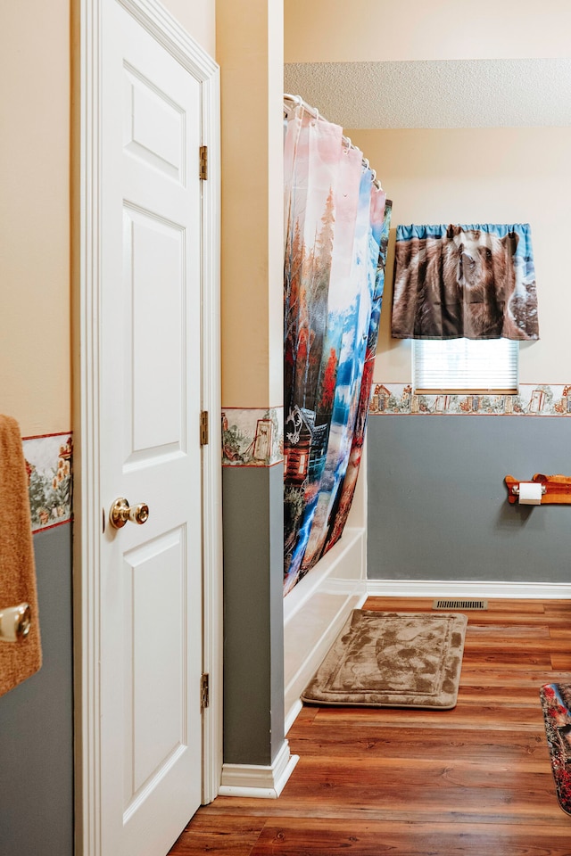 bathroom featuring shower / bath combo with shower curtain, hardwood / wood-style flooring, and a textured ceiling