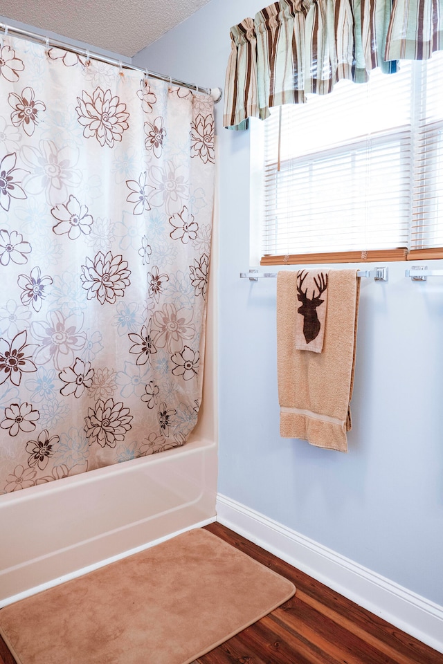 bathroom featuring a textured ceiling, a healthy amount of sunlight, shower / bath combo with shower curtain, and hardwood / wood-style floors