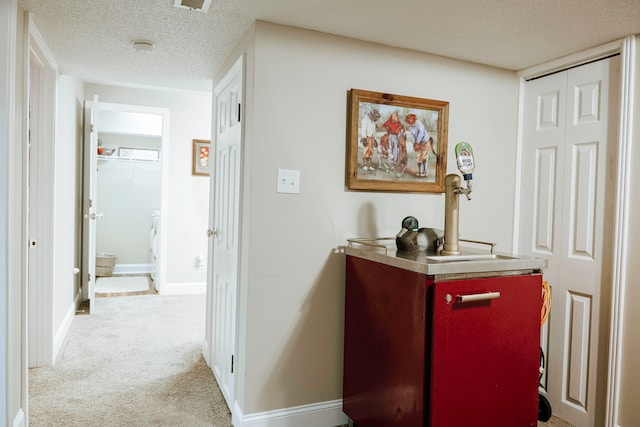 corridor with a textured ceiling and carpet flooring