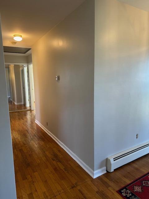 corridor with baseboards, dark wood-type flooring, and baseboard heating