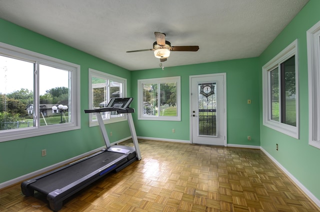 exercise area with a textured ceiling, baseboards, and a ceiling fan