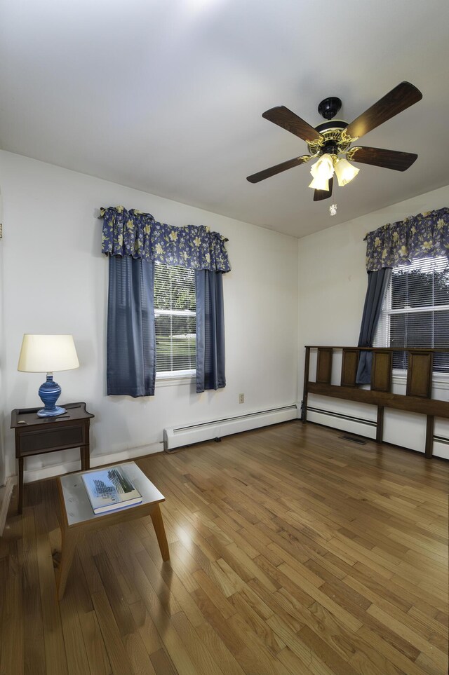 sitting room with a ceiling fan, wood finished floors, and a baseboard radiator