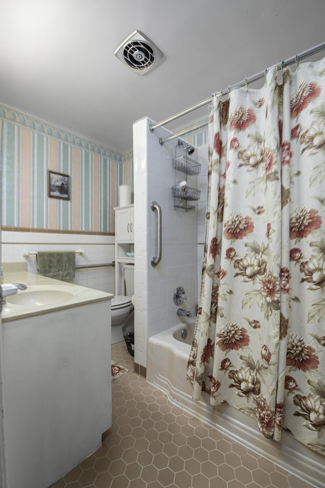 full bathroom with visible vents, wallpapered walls, toilet, shower / bath combo with shower curtain, and vanity