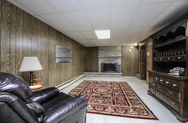 living room with wooden walls, a fireplace, a baseboard heating unit, and a paneled ceiling