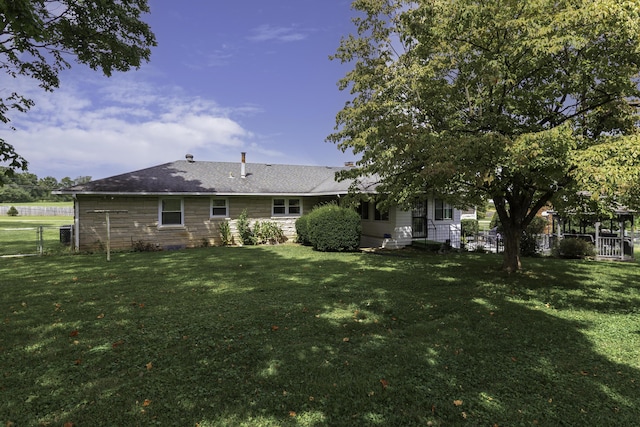 back of property featuring a yard and fence