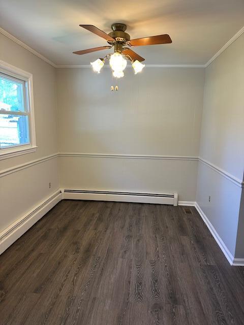 spare room featuring a ceiling fan, crown molding, wood finished floors, and baseboards