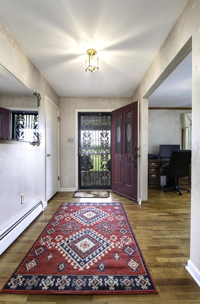 entrance foyer with a baseboard heating unit, wood finished floors, and baseboards