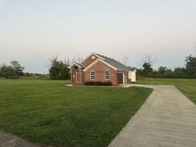 view of side of home featuring an attached garage, a yard, brick siding, and concrete driveway