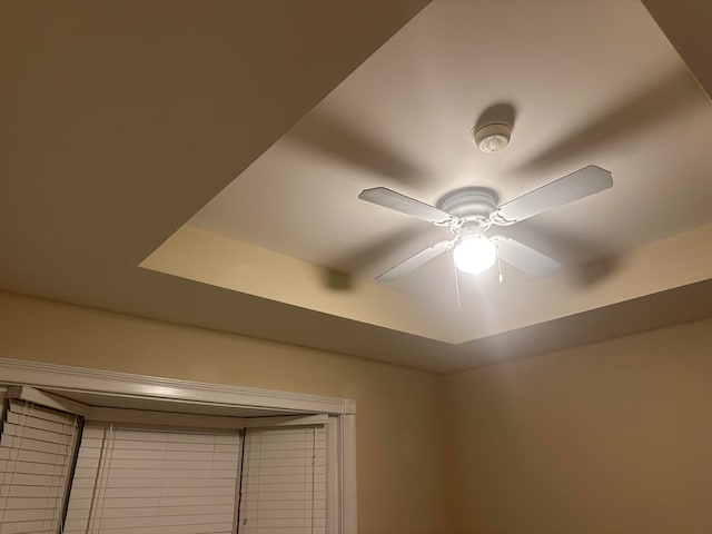 room details featuring ceiling fan and a tray ceiling