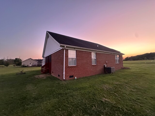 property exterior at dusk featuring central AC unit and a yard