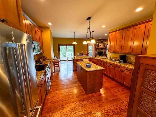 kitchen featuring pendant lighting, hardwood / wood-style floors, a center island, stainless steel appliances, and kitchen peninsula