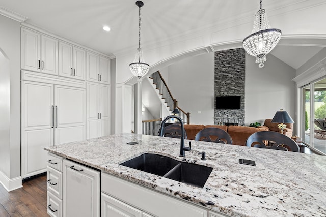 kitchen with vaulted ceiling, dark hardwood / wood-style flooring, a notable chandelier, a stone fireplace, and sink