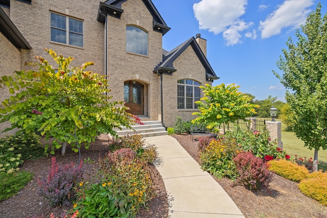 view of front of home featuring brick siding and a chimney