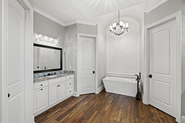 bathroom featuring vanity, an inviting chandelier, wood-type flooring, ornamental molding, and a washtub