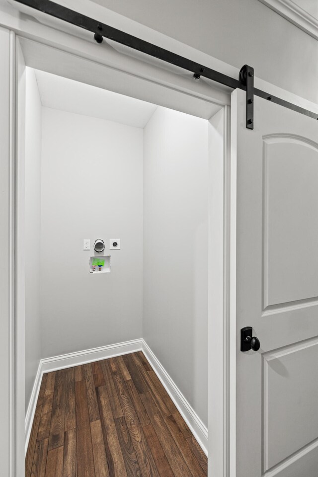 washroom with a barn door, hookup for a washing machine, hookup for an electric dryer, and dark hardwood / wood-style floors