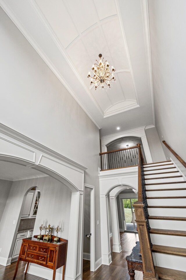 staircase featuring crown molding, hardwood / wood-style flooring, and a notable chandelier