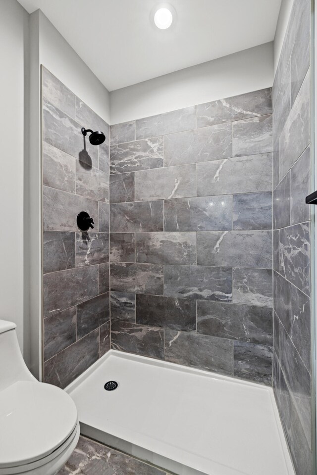 bathroom featuring tiled shower and toilet