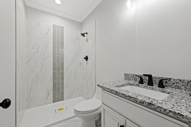 bathroom with ornamental molding, vanity, toilet, and tiled shower