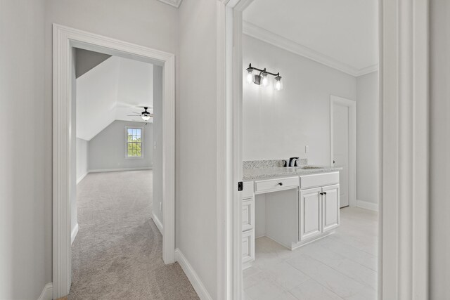 corridor with light carpet, lofted ceiling, ornamental molding, and sink