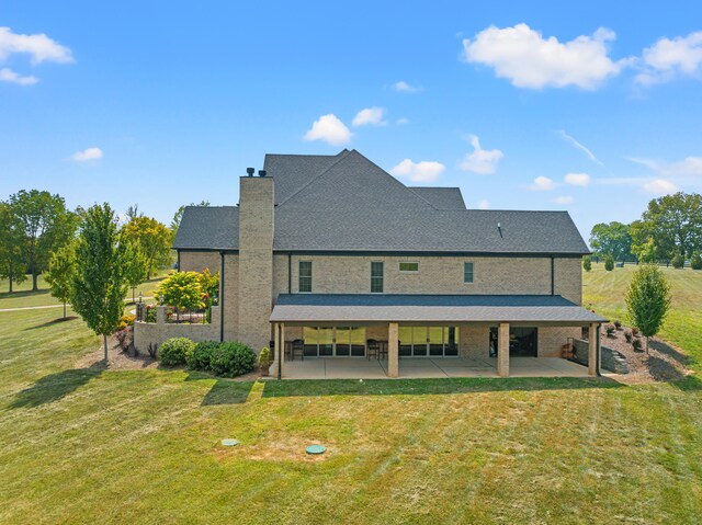 rear view of house featuring a lawn and a patio