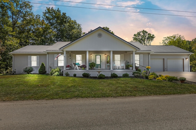 ranch-style home featuring a lawn, a garage, and covered porch