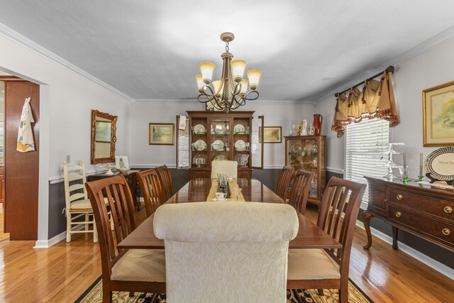 dining room with an inviting chandelier, crown molding, and light hardwood / wood-style floors