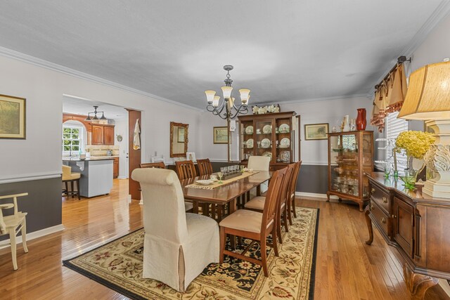 dining space with light hardwood / wood-style floors, ornamental molding, and a chandelier