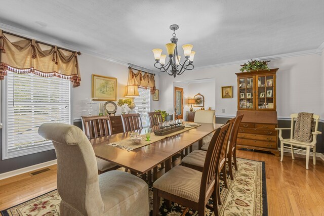 dining room with ornamental molding, an inviting chandelier, and light hardwood / wood-style floors