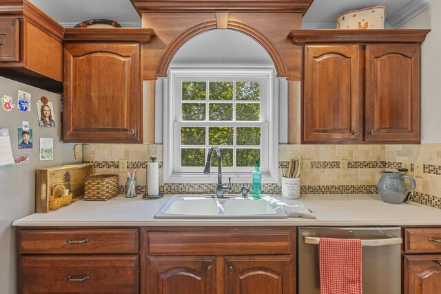 kitchen with backsplash, dishwasher, crown molding, and sink