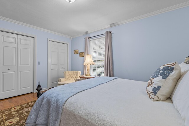 bedroom with ornamental molding, multiple closets, and hardwood / wood-style flooring